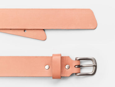 A close-up of a light tan leather belt with a silver buckle, displayed on a white background. The belt is laid out flat, showing both the buckle and the pointed end.