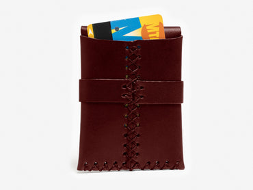 A brown leather card holder with visible stitching, holding two colorful cards partially sticking out from the top, against a white background.