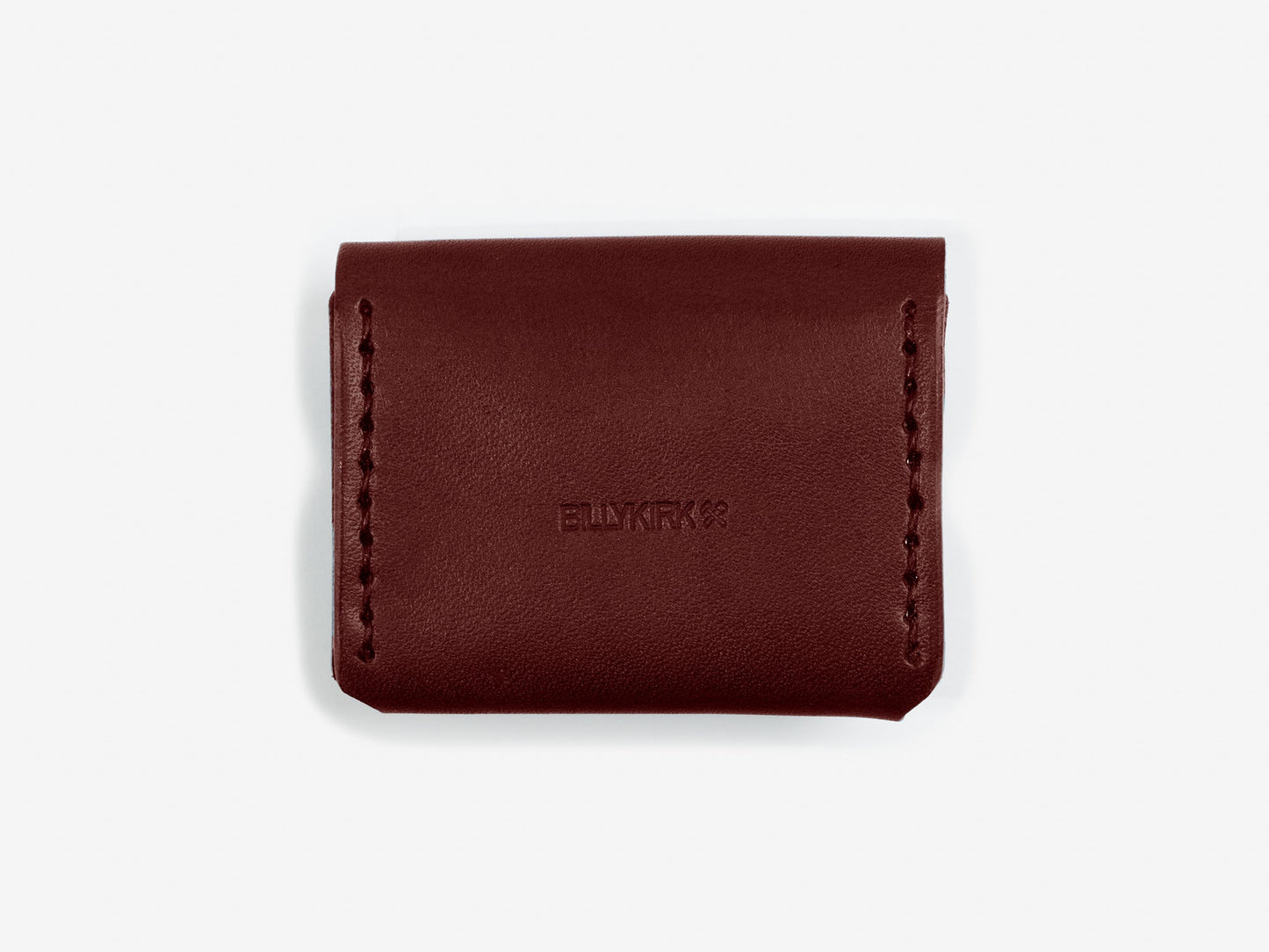 The back of a burgundy leather coin pouch showing the Billykirk logo stamped in the leather on an off-white background
