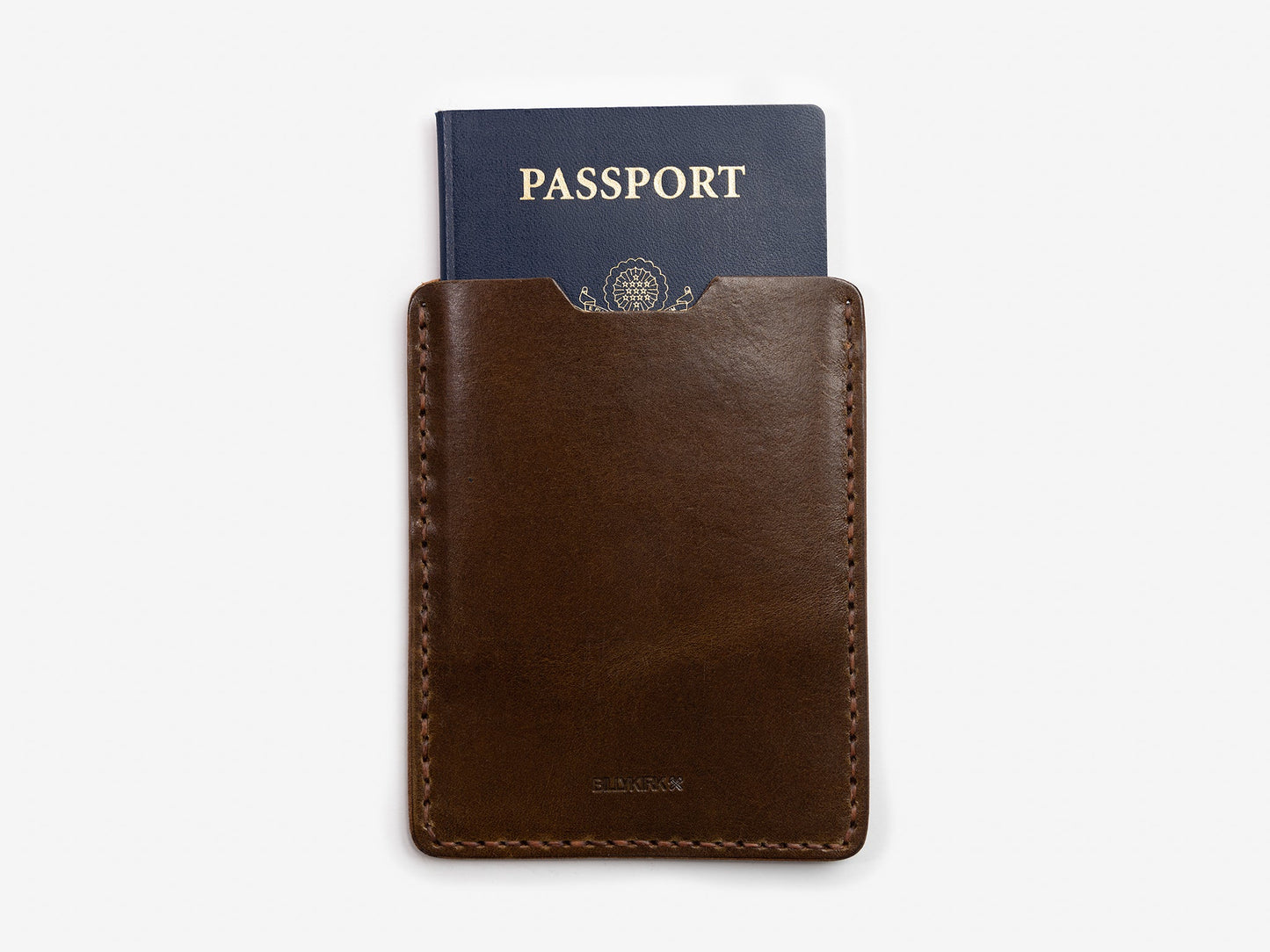 A dark brown leather passport holder with a blue passport partially visible inside, set against a plain white background.