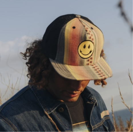 Native American designed Trucker hat with smiling face patch and sunset stripes by Steven Paul Judd