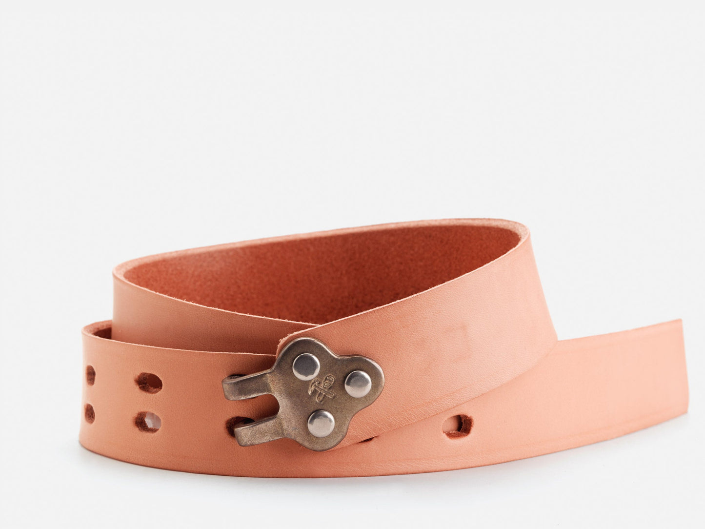 A rolled-up tan leather belt featuring a unique metal buckle shaped like a wind-up key, with multiple adjustment holes visible.