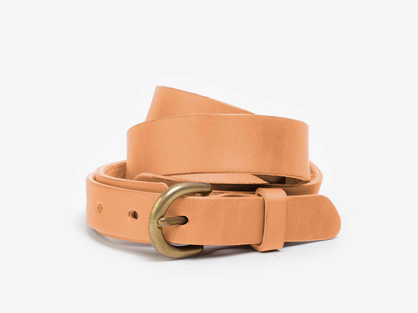 A tan leather belt with a brass buckle is coiled neatly against a plain white background.