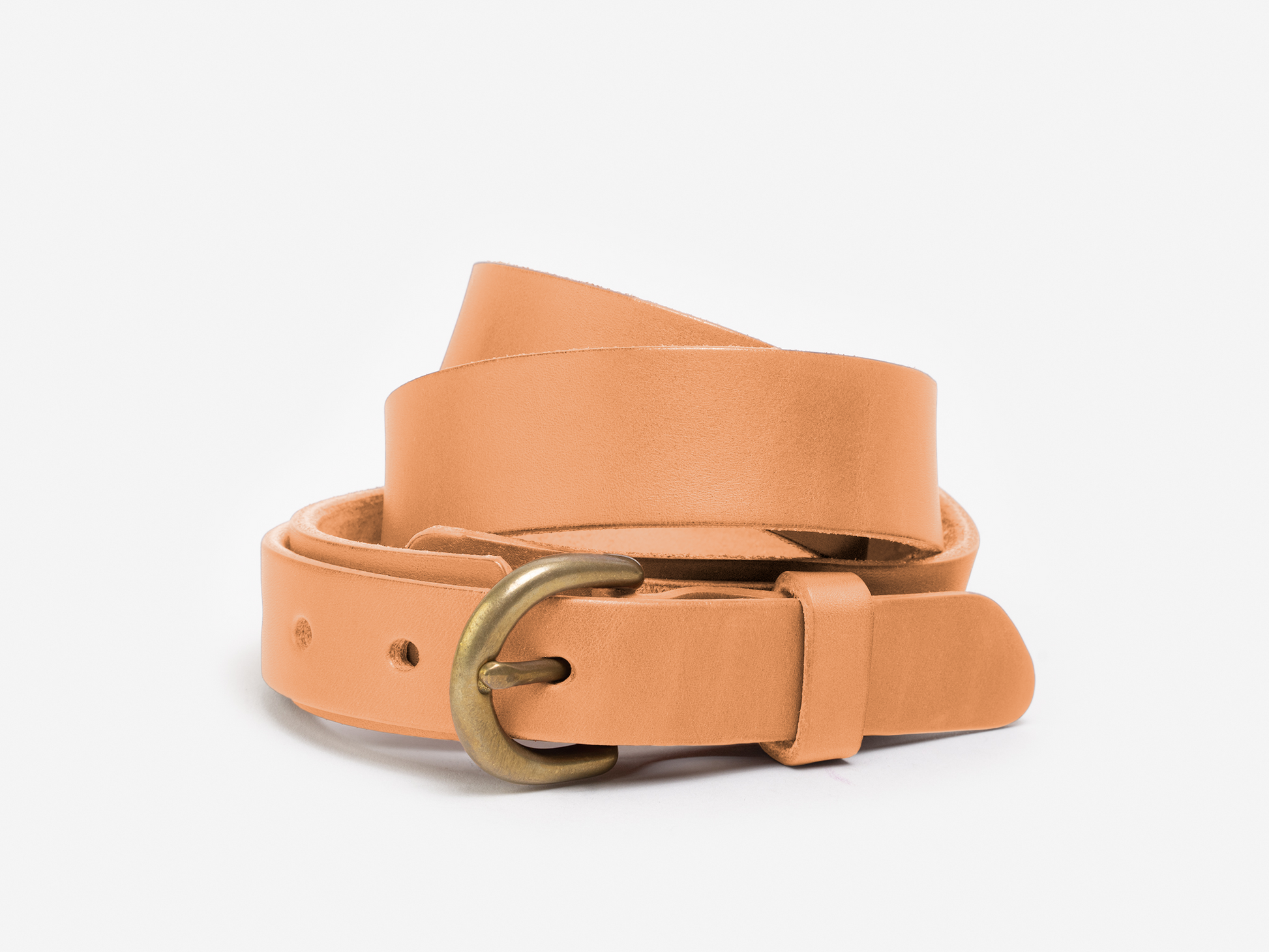 A tan leather belt with a brass buckle is coiled neatly against a plain white background.