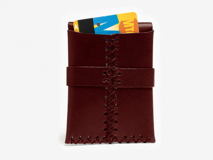 A brown leather card holder with visible stitching, holding two colorful cards partially sticking out from the top, against a white background.