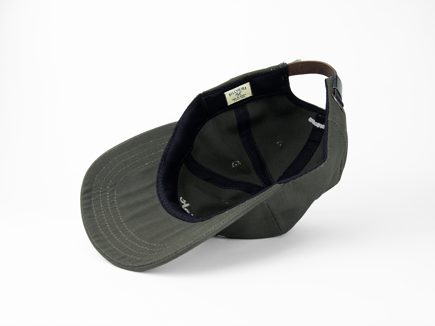 The inside view of an olive baseball cap featuring a woven tag that reads "Billykirk"