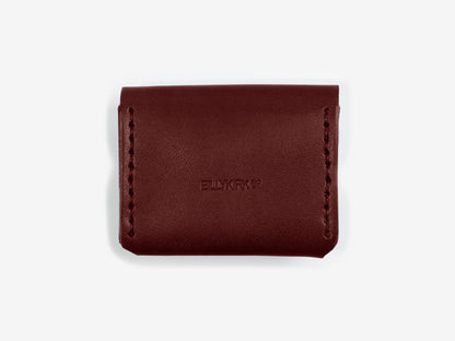 The back of a burgundy leather coin pouch showing the Billykirk logo stamped in the leather on an off-white background