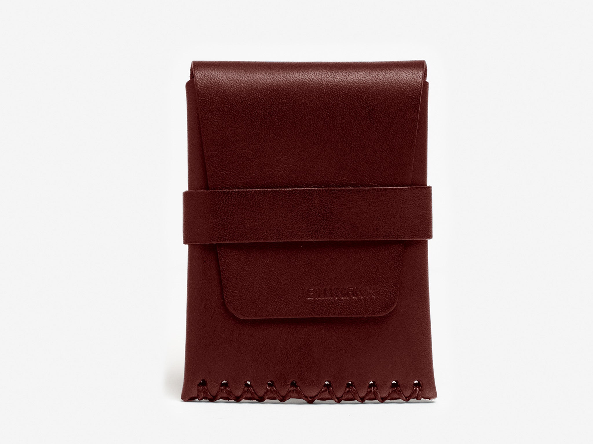 A burgundy leather card case with a flap closure, wide strap across the front, and decorative stitching along the bottom edge, placed against a plain white background.