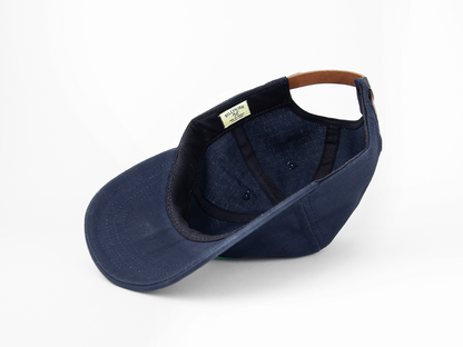 A navy blue baseball cap turned upside down, showing its interior lining, black sweatband, and brown adjustable strap at the back on a white background.