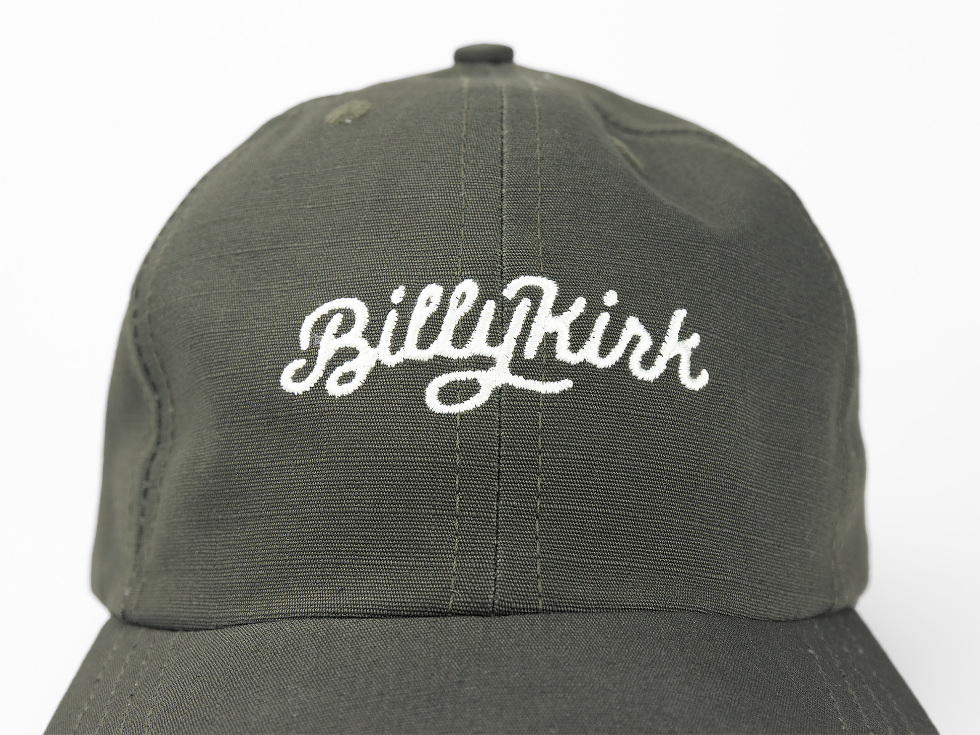 An olive baseball cap featuring a white cursive embroidery on the front that reads “Billykirk”.