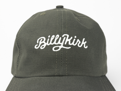 An olive baseball cap featuring a white cursive embroidery on the front that reads “Billykirk”.
