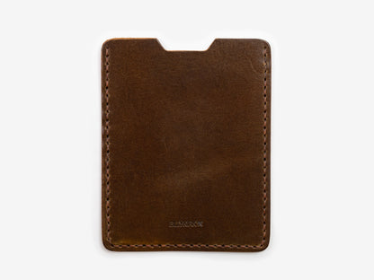 A slim, brown leather card holder with visible stitching around the edges, photographed on a white background.