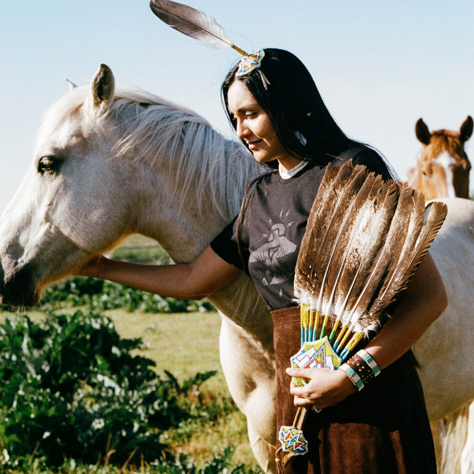 Indigenous Ginew's black cotton  thunderbird tshirt on Native American women with horse 