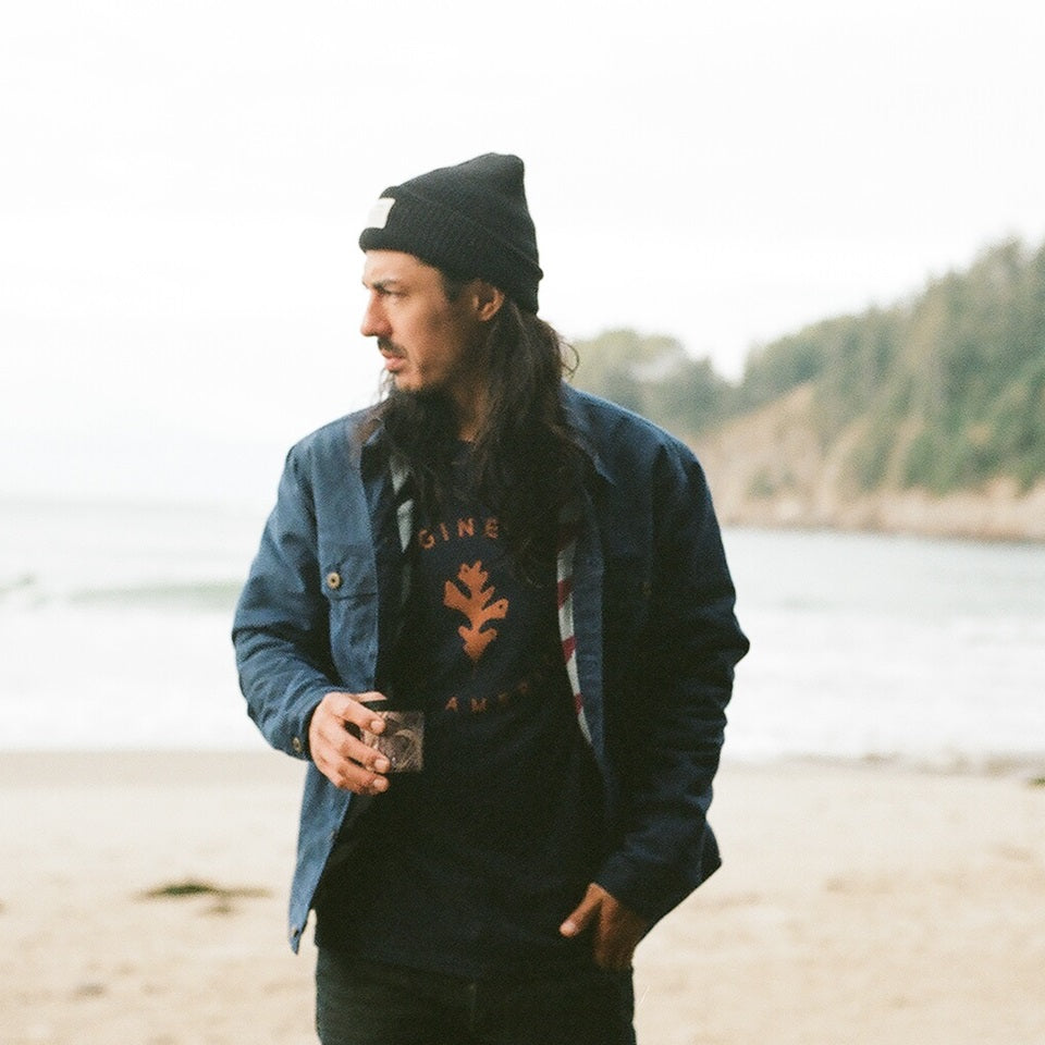 Navy t-shirt with brown oakleaf on Native American model wearing wax canvas coat and wool cap