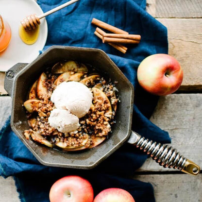 Finex skillet with roasted apples and walnuts topped with ice cream set on a decorative table