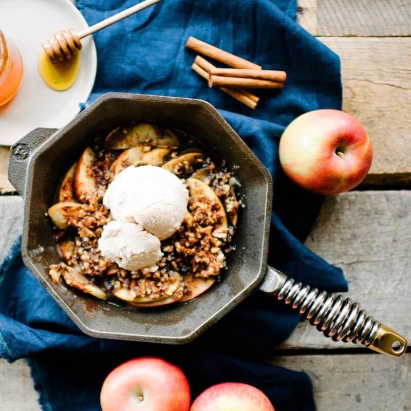 Finex skillet with roasted apples and walnuts topped with ice cream set on a decorative table