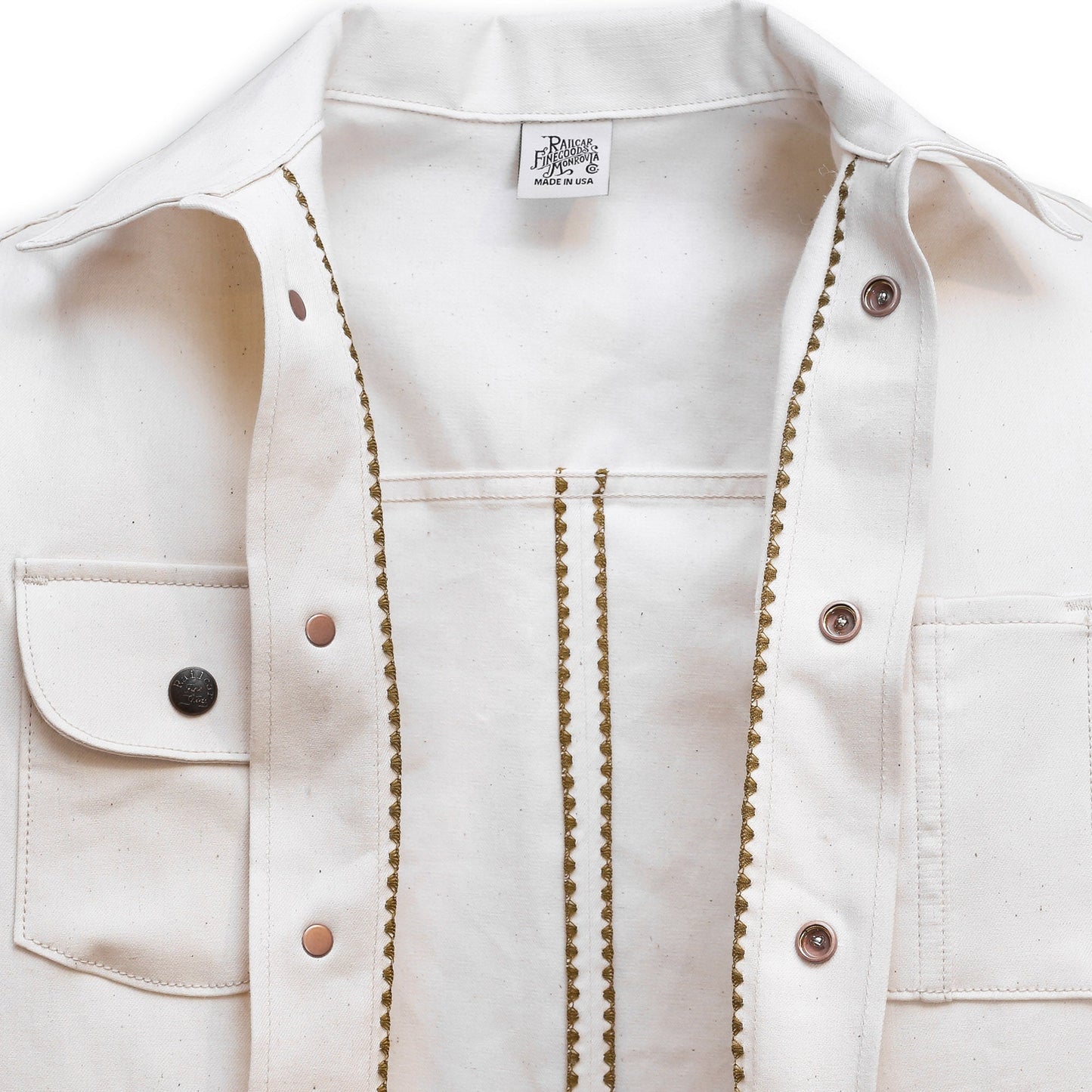 Interior of a natural seed chore coat with snap buttons, featuring a collar, front pockets, and shelling detail.