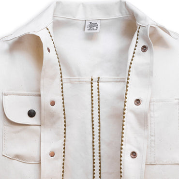 Interior of a natural seed chore coat with snap buttons, featuring a collar, front pockets, and shelling detail.