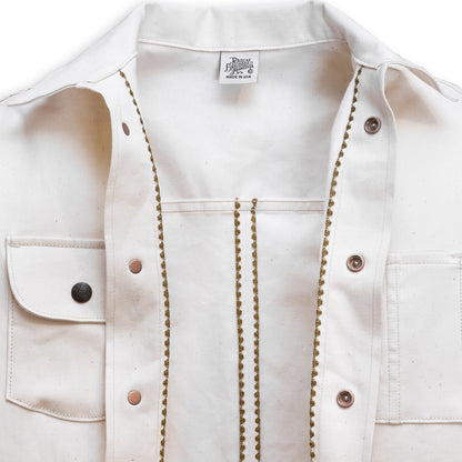 Interior of a natural seed chore coat with snap buttons, featuring a collar, front pockets, and shelling detail.